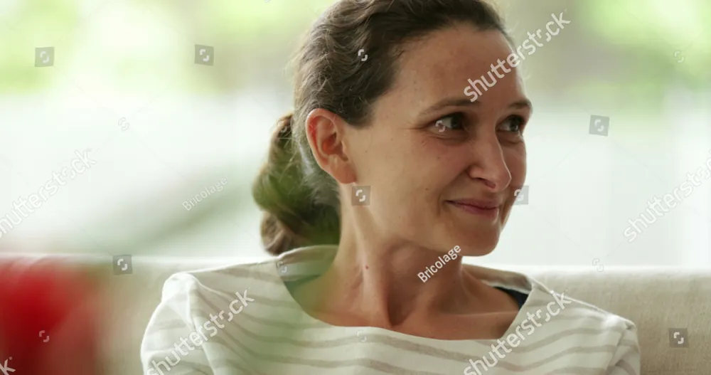 A woman with her hair pulled back, smiling softly as she looks to the side