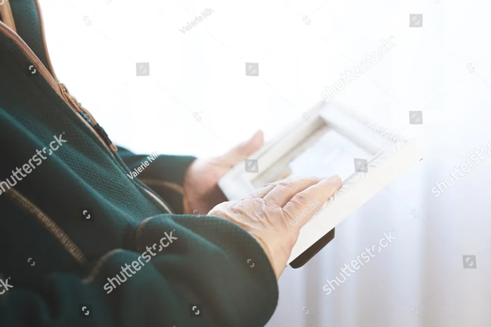 Hands holding a framed photograph near a window