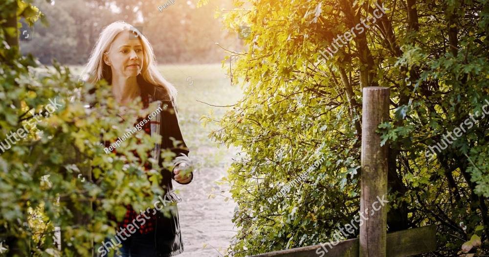 A woman walking through a garden in the golden evening light