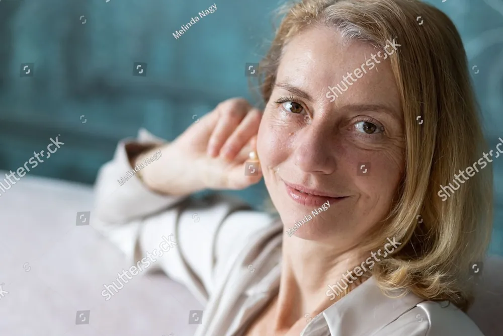 A smiling woman relaxing on a sofa, one hand resting behind her head