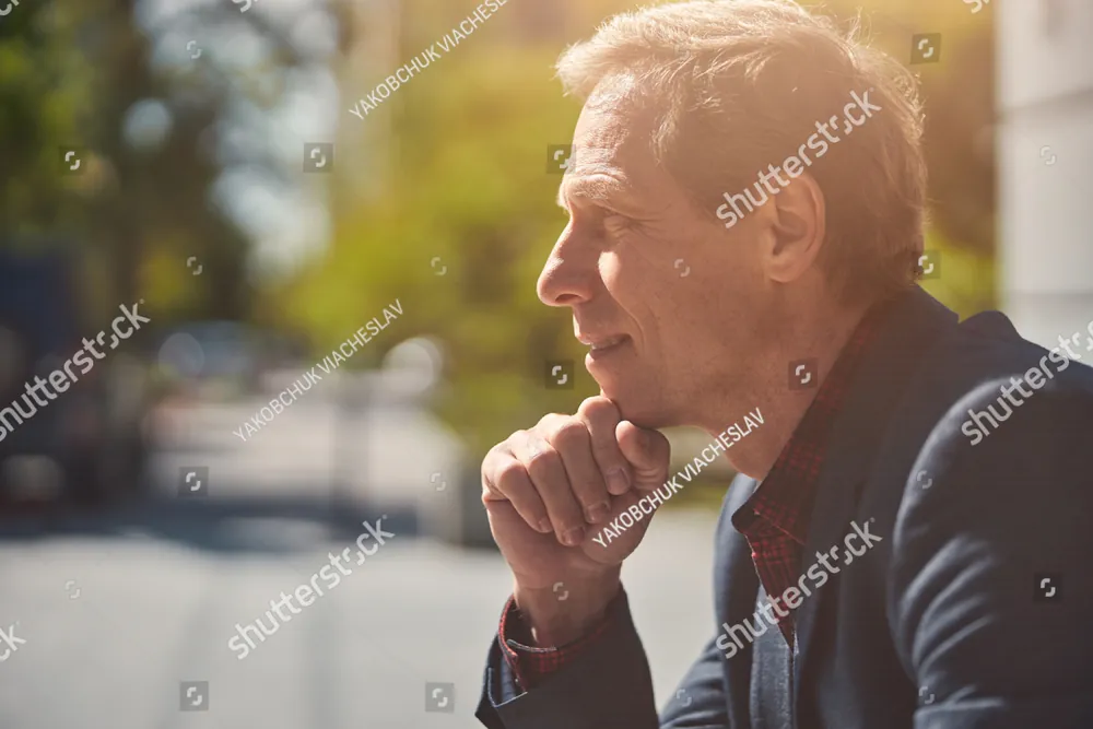 A grey-haired man with his hand at his chin, deep in thought