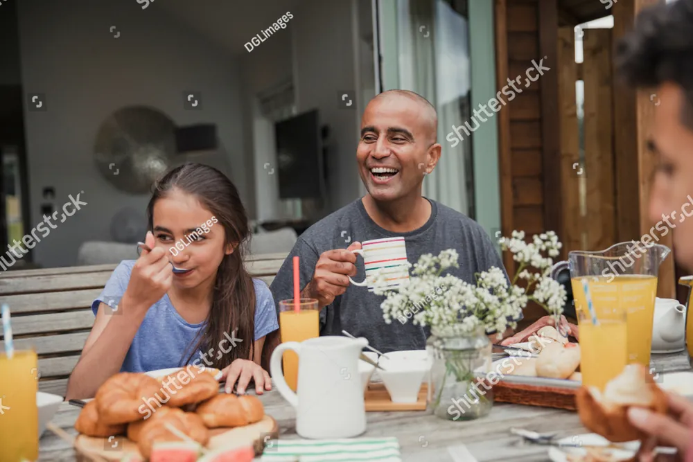 A family laughing together over breakfast at an outdoor table
