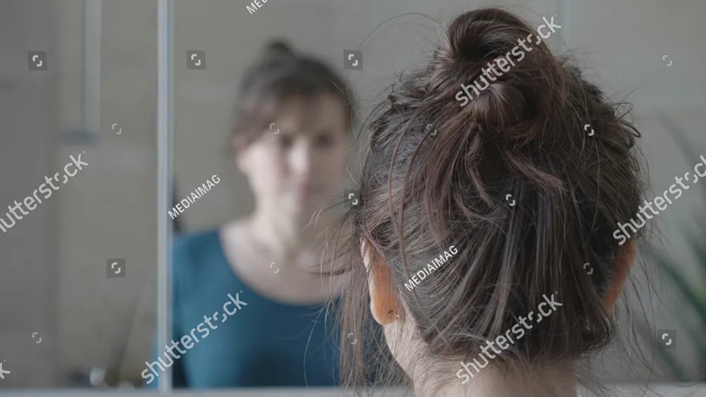 A woman with her hair in a bun, turned away from a woman behind her